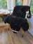 Adorable black bear rug shaped like a fluffy sheep chair cover made of soft merino sheepskin with wooden legs