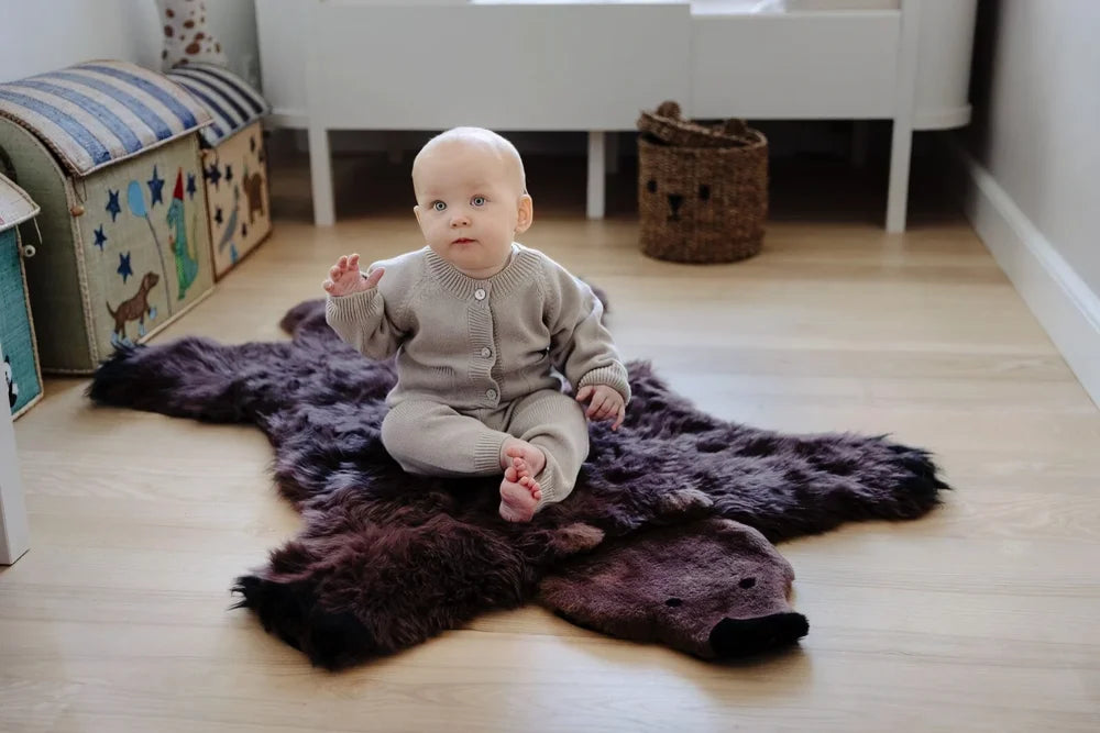 A plush dark purple grizzly bear rug made of soft merino sheepskin with shaggy fur perfect for cozy spaces