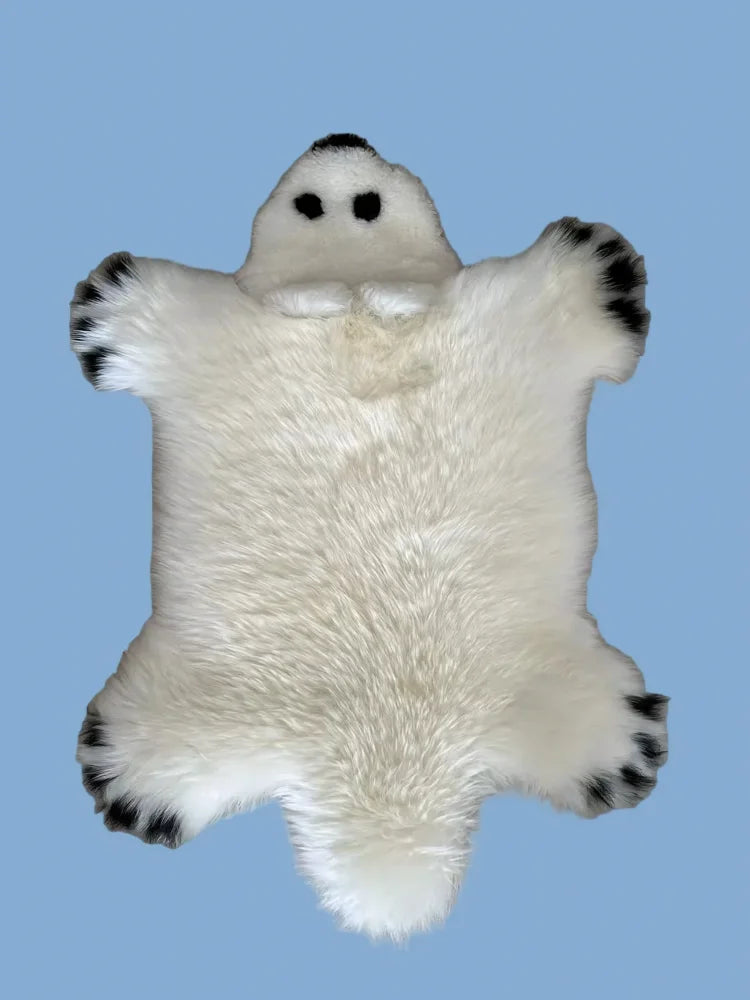 Adorable white merino sheepskin polar bear rug with black paw pads and embroidered eyes perfect for cozy decor