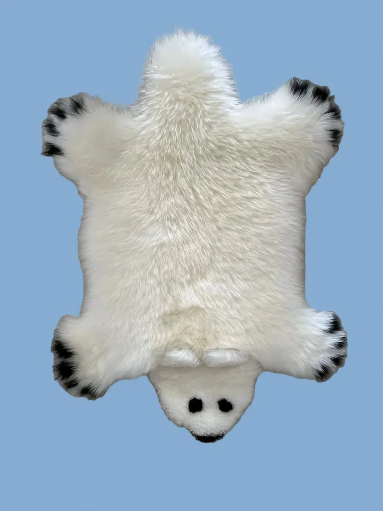 Adorable merino sheepskin polar bear rug with white faux fur and black tipped paws and nose perfect for cozy decor