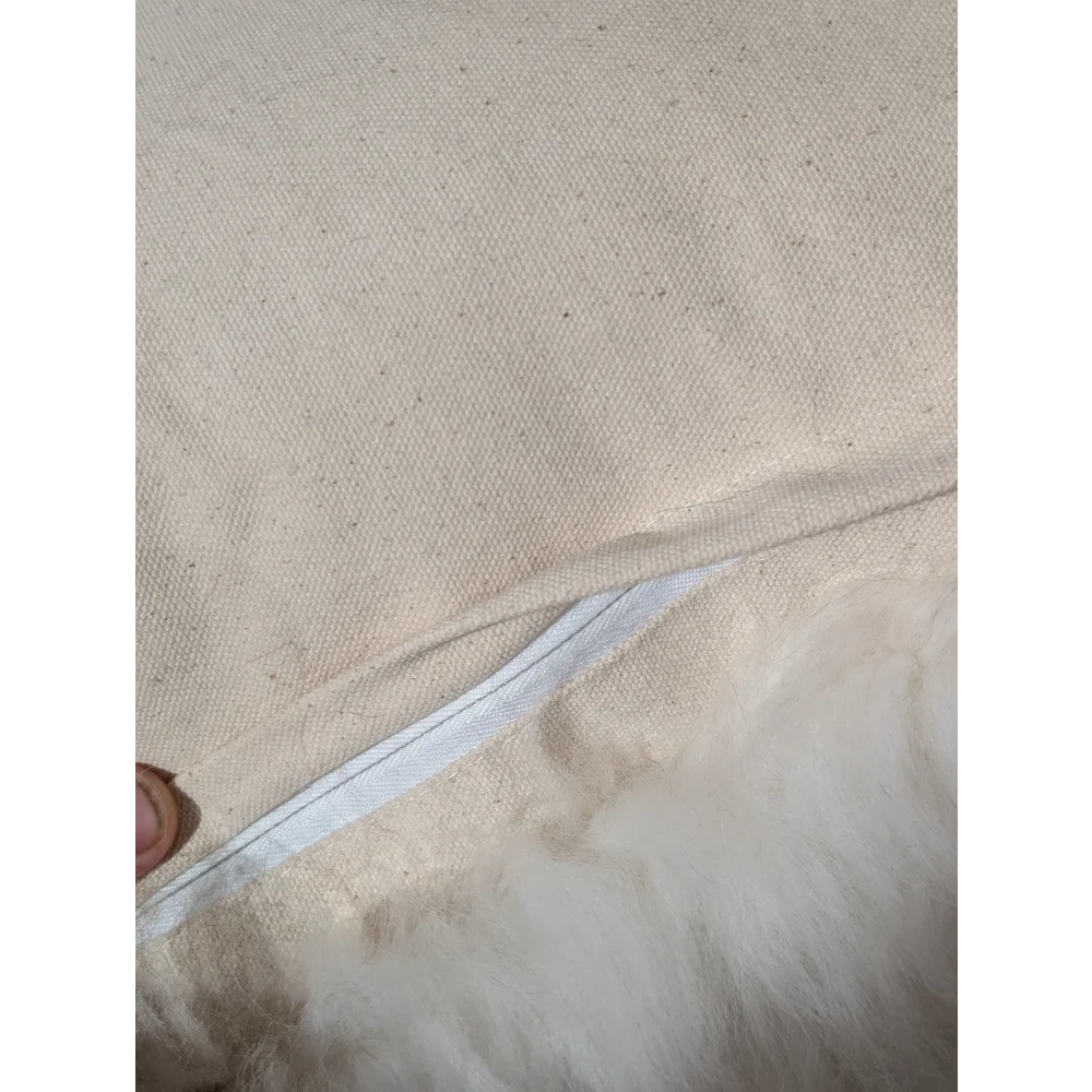 Beige canvas pillow with white zipper and fluffy white interior from adorable set of sheepskin cushions by angus oliver canada