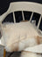 Cream-colored linen pillow resting on white chair with fluffy off-white sheepskin in adorable angus oliver canada set