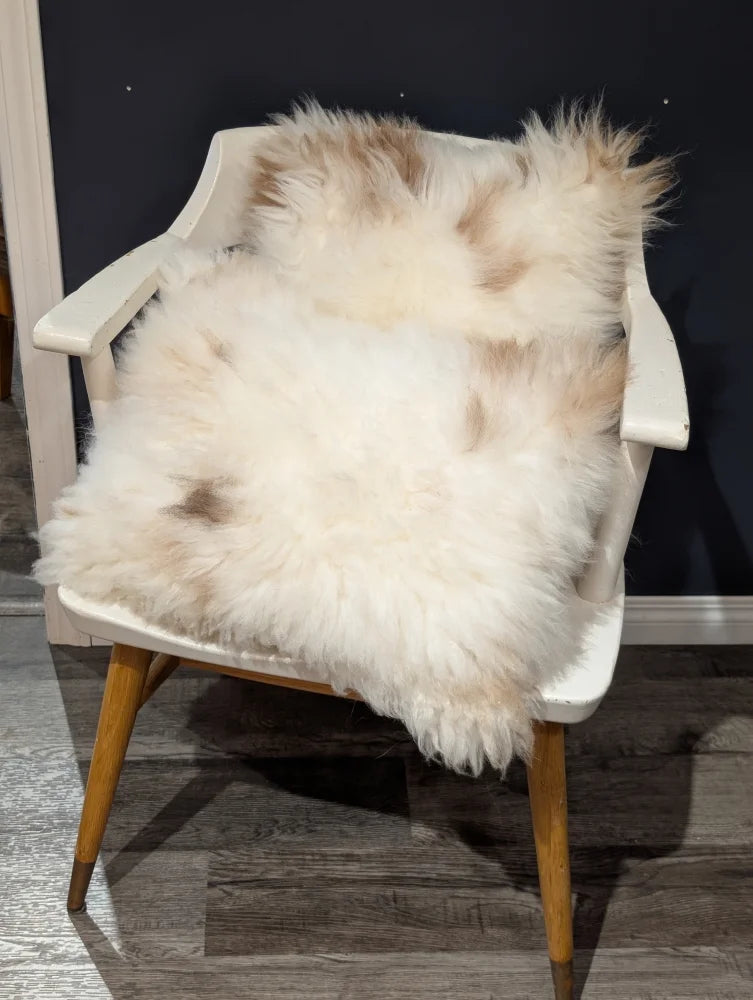 Adorable set of cream and beige sheepskin cushions draped over white wooden chair by angus oliver canada with soft texture