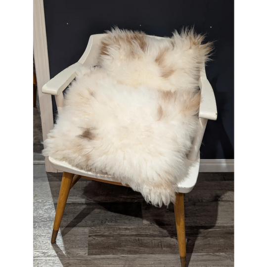 Adorable set of cream and beige sheepskin cushions draped over white wooden chair by angus oliver canada with soft texture