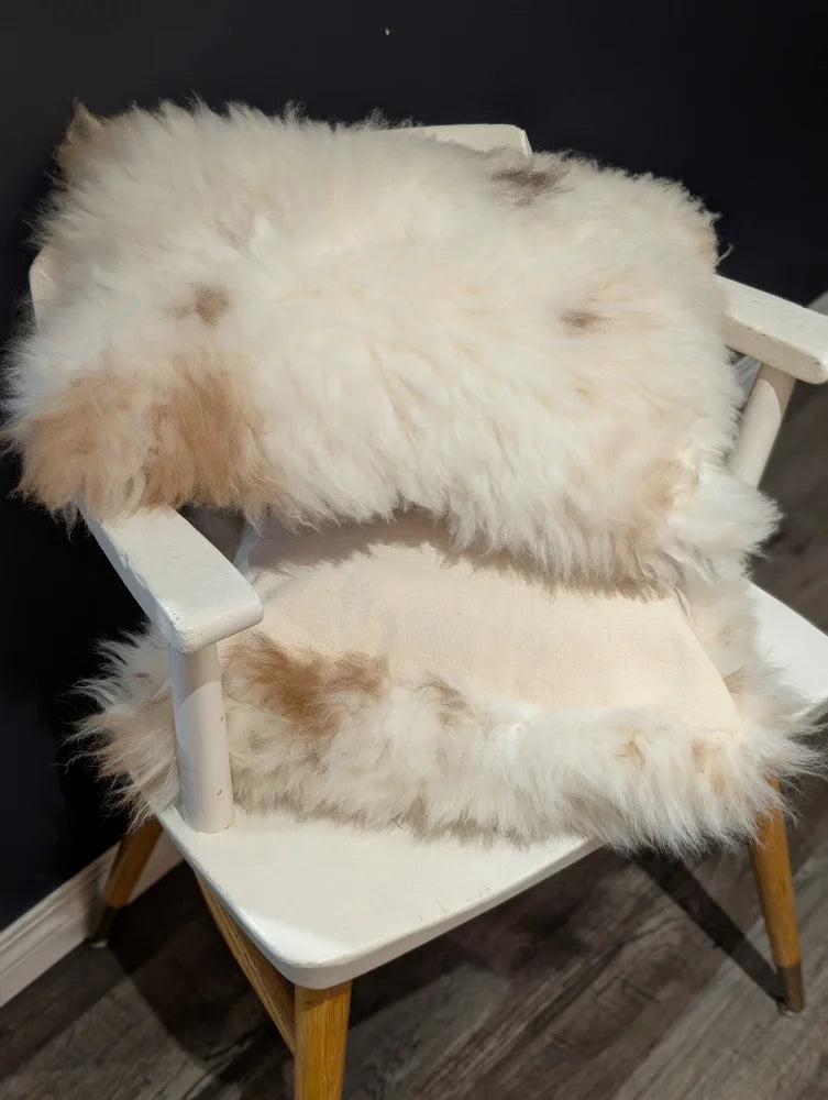 Fluffy white and beige sheepskin rug draped over white wooden chair from angus oliver canada sheepskin rugs collection