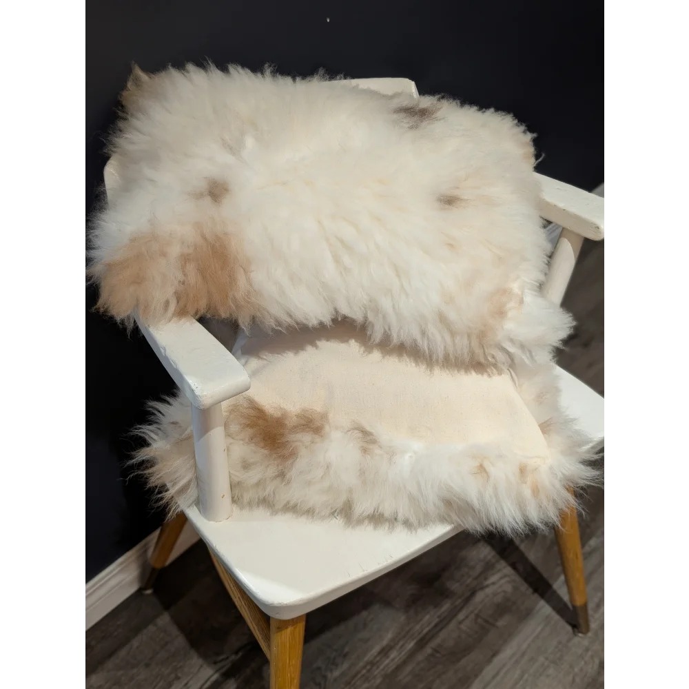 Fluffy white and beige sheepskin rug draped over white wooden chair from angus oliver canada sheepskin rugs collection