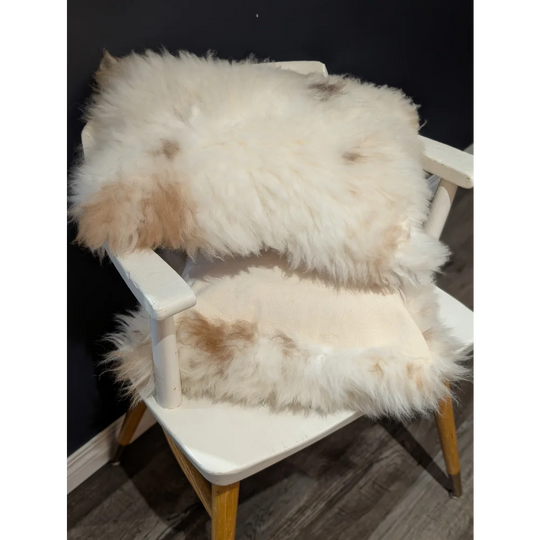 Fluffy white and beige sheepskin rug draped over white wooden chair from angus oliver canada sheepskin rugs collection
