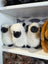 Three plush white mini sheep soft toys with black faces and legs neatly arranged on a shelf