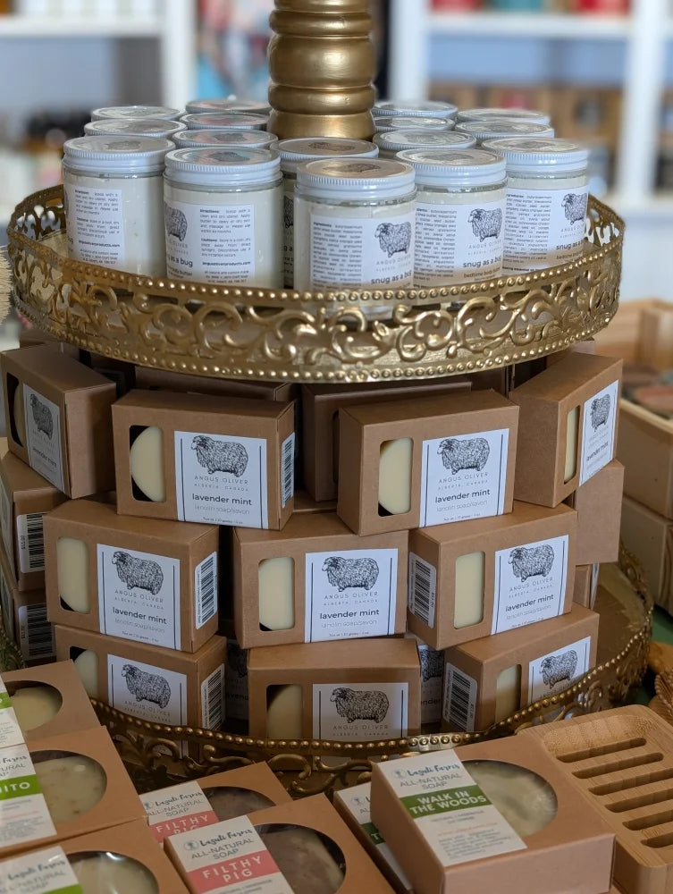 Golden tiered stand with lanolin soap bars in glass jars and kraft packaging