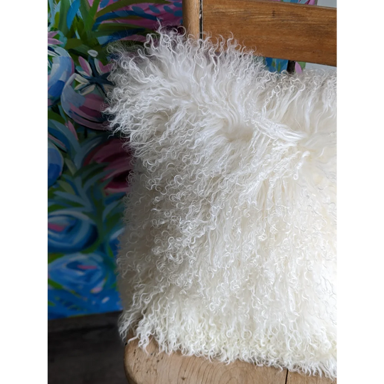 White fluffy Mongolian sheepskin cushion on wooden chair