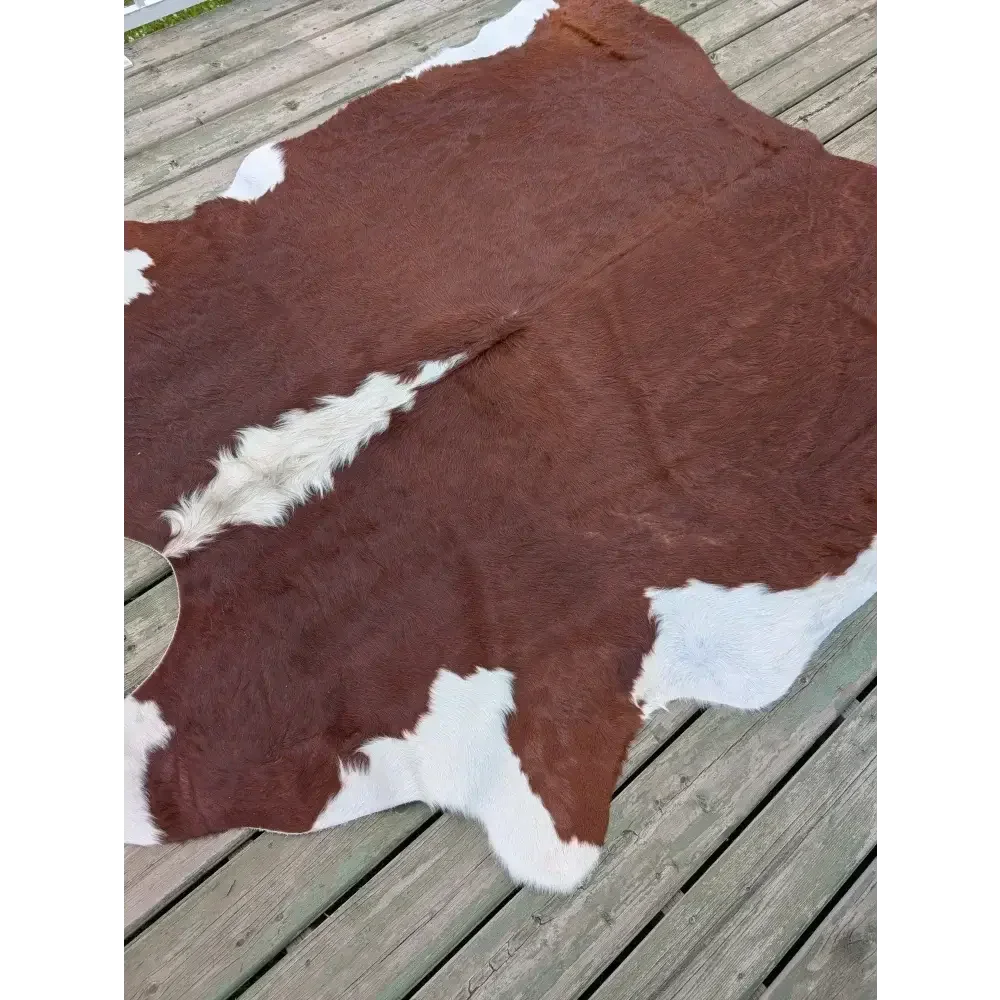 Large ASM#128 brown and white cowhide rug on wooden deck, soft underfoot