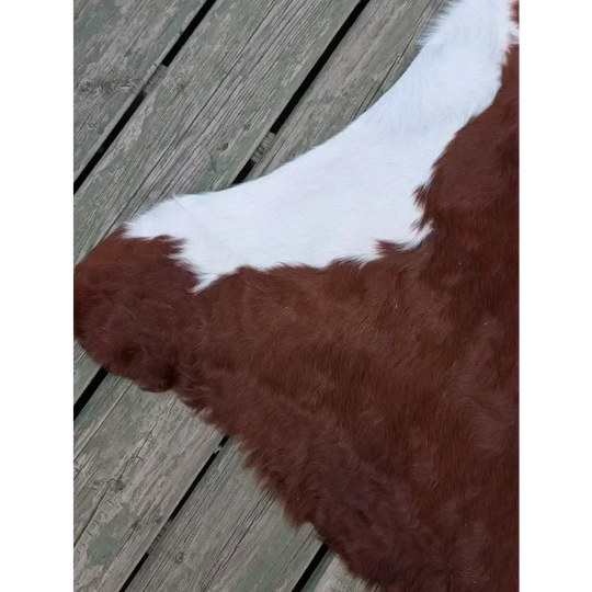 Large ASM#128 brown and white cowhide rug on wooden deck, soft underfoot