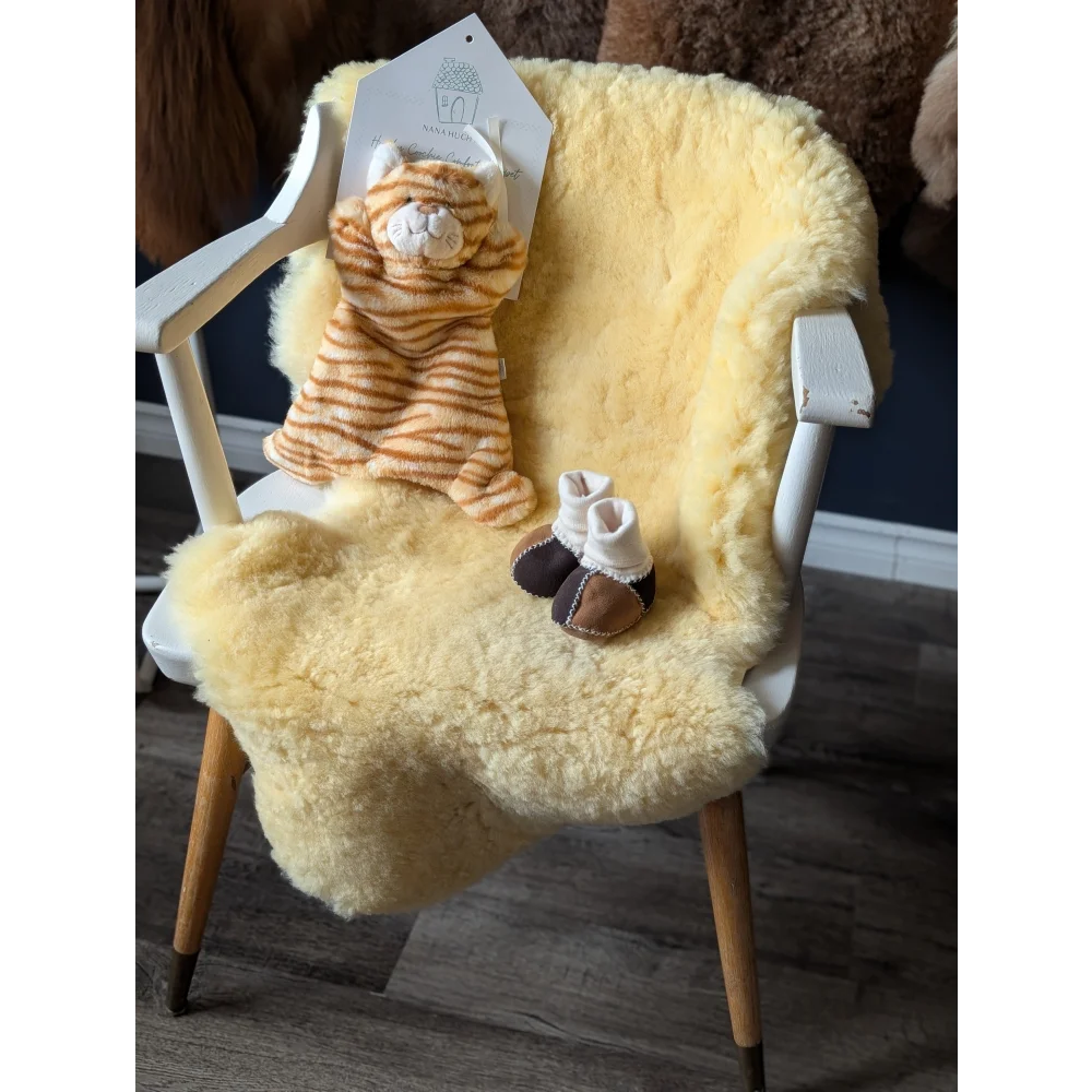 White wooden chair with yellow medical sheepskin rug, plush toy, and baby booties