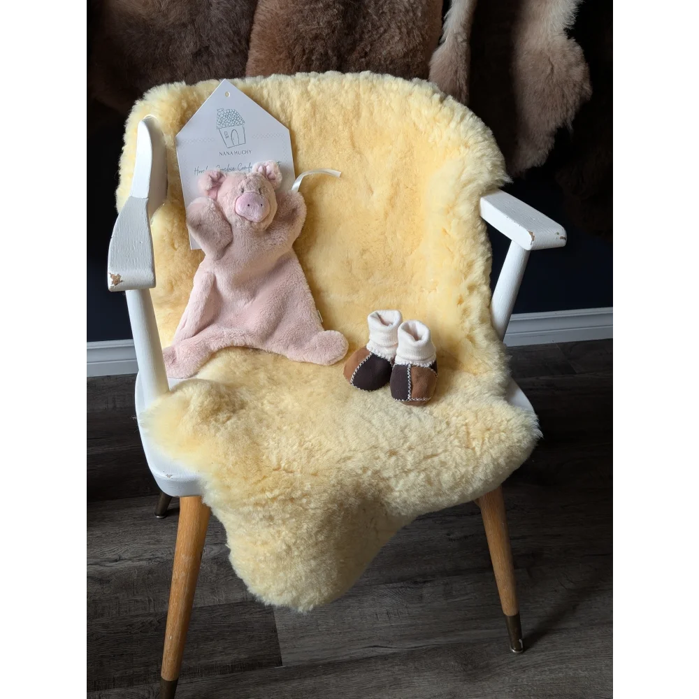 Baby Gift Set with white wooden chair, yellow medical sheepskin throw, pink pig toy, and baby booties
