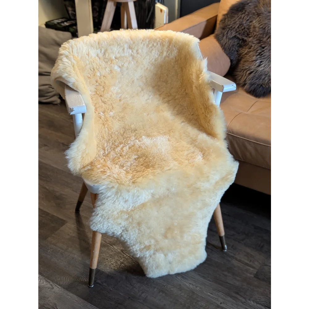 Cream-colored extra large medical sheepskin rug draped on white wooden chair by angus oliver canada