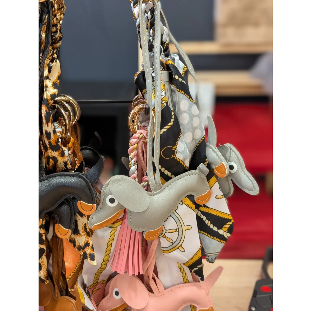 Grey dachshund bag charm by Angus Oliver with orange accents, pink tassel