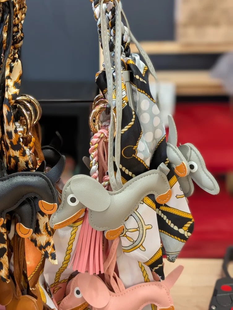 Grey dachshund bag charm by Angus Oliver with orange accents, pink tassel