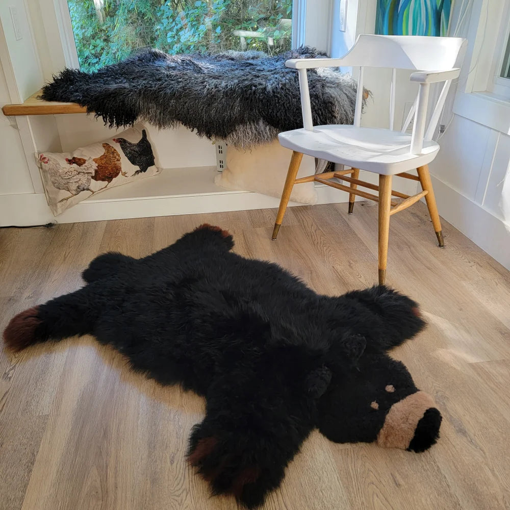 Black faux fur bear rug made from sheepskin with tan snout and brown paw tips perfect for cozy decor