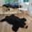Black faux fur bear rug made from sheepskin with tan snout and brown paw tips perfect for cozy decor