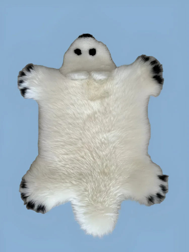 White faux fur polar bear rug with black paw pads and embroidered eyes made from sheepskin for cozy decor