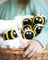 Bee trio eco wool dryer balls shaped like yellow and black bees with embroidered eyes in a white towel basket