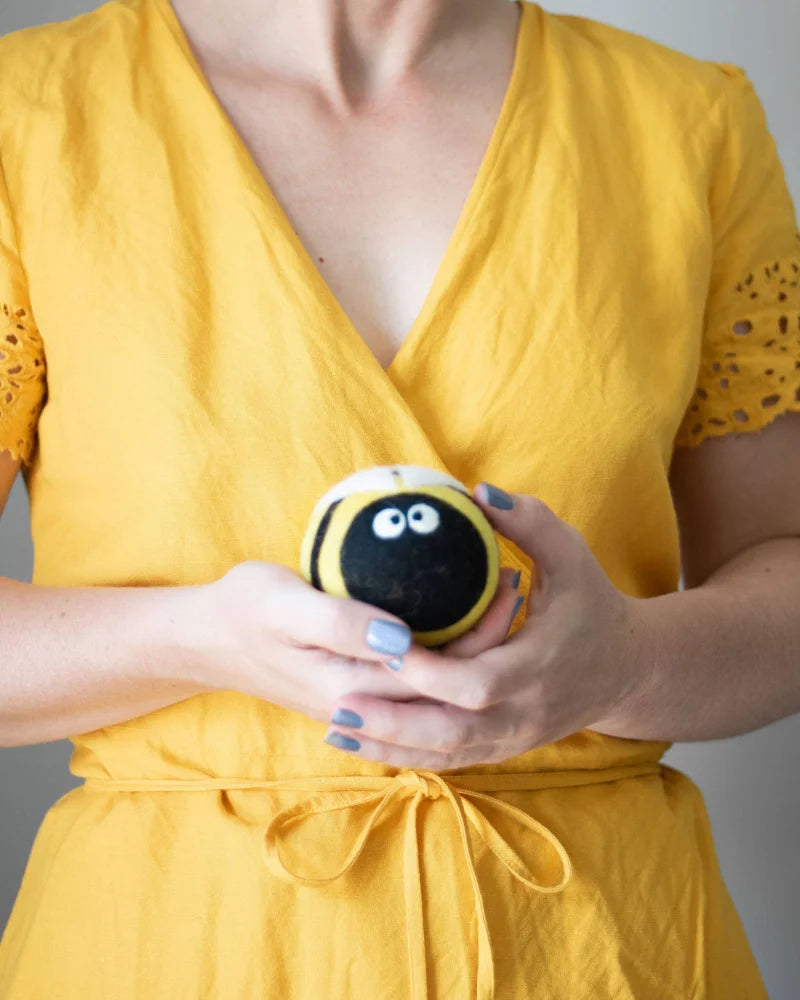 A plush bee trio eco dryer ball in black and yellow stripes with white eyes made from soft wool fabric for drying clothes