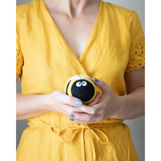 A plush bee trio eco dryer ball in black and yellow stripes with white eyes made from soft wool fabric for drying clothes