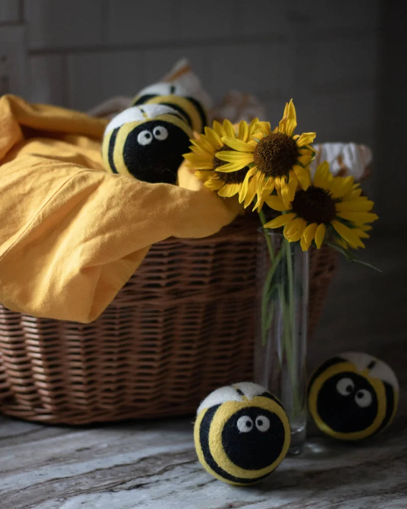 Yellow and black fuzzy bee trio eco dryer balls made of wool with embroidered eyes and storage bag for laundry use