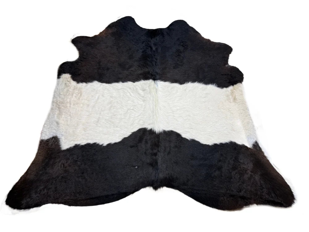 Large black and white cowhide rug with natural irregular edge featuring unique characteristics for beautiful rugs