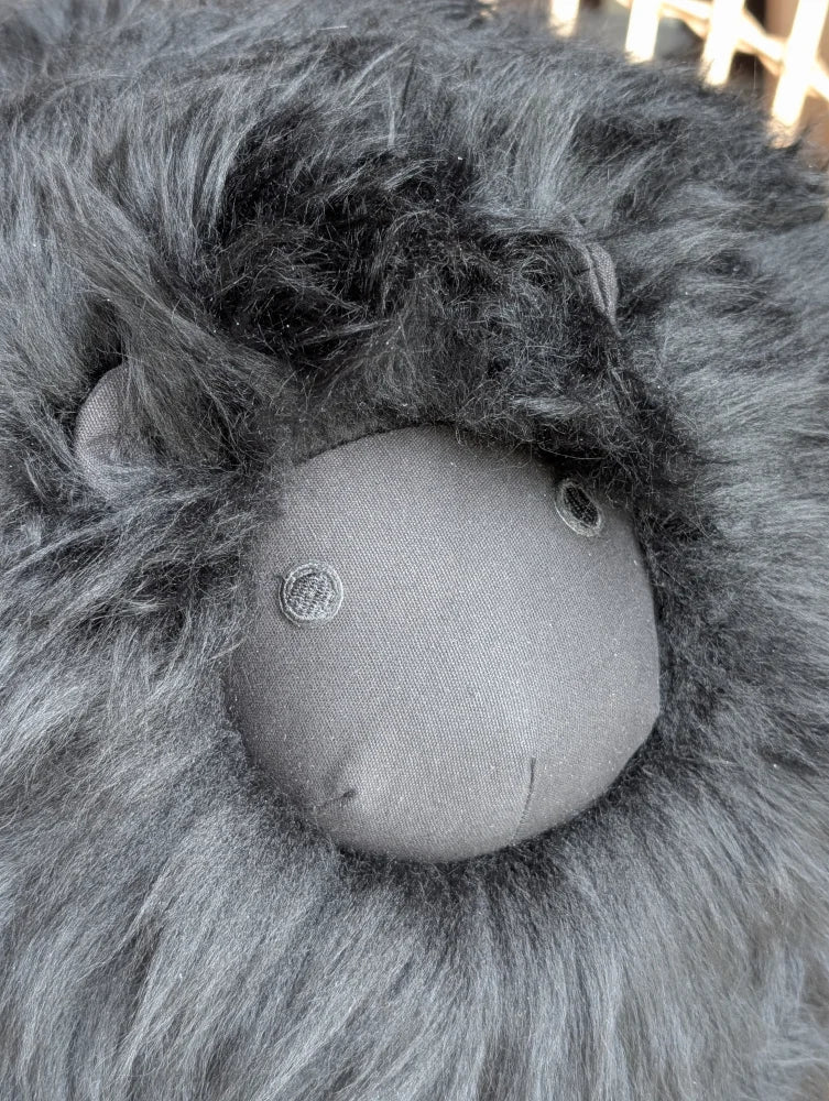 A plush gray rotund sheep cushion with a soft fluffy mane made from merino sheepskin for cozy decor