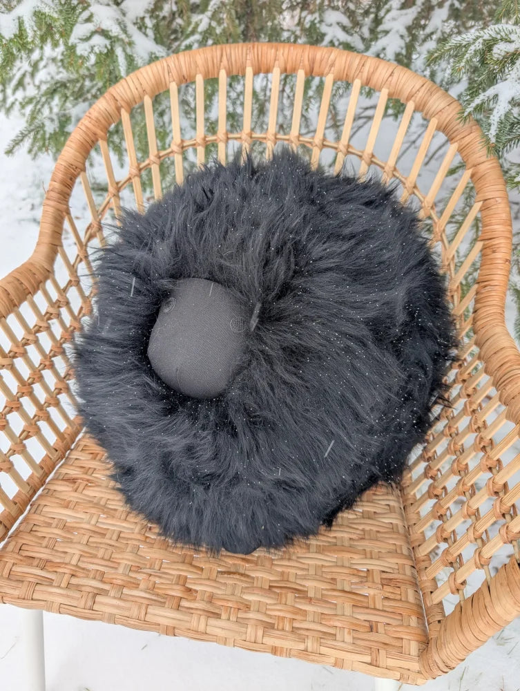 Black rotund sheep cushion with plush dark gray faux fur and solid black inner lining for cozy merino sheepskin feel