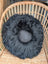 Black rotund sheep cushion made of soft merino sheepskin with fluffy texture and embroidered facial features