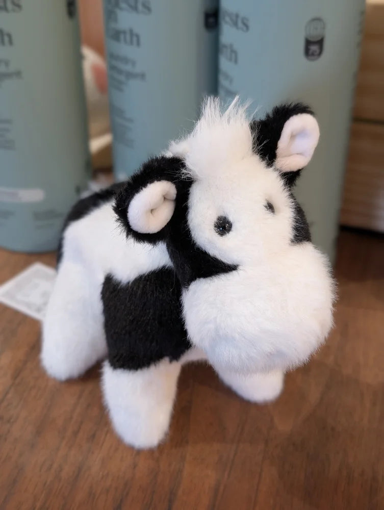 A plush black white cow toy with soft fluffy fur and a giant snuggly muzzle perfect for cuddling