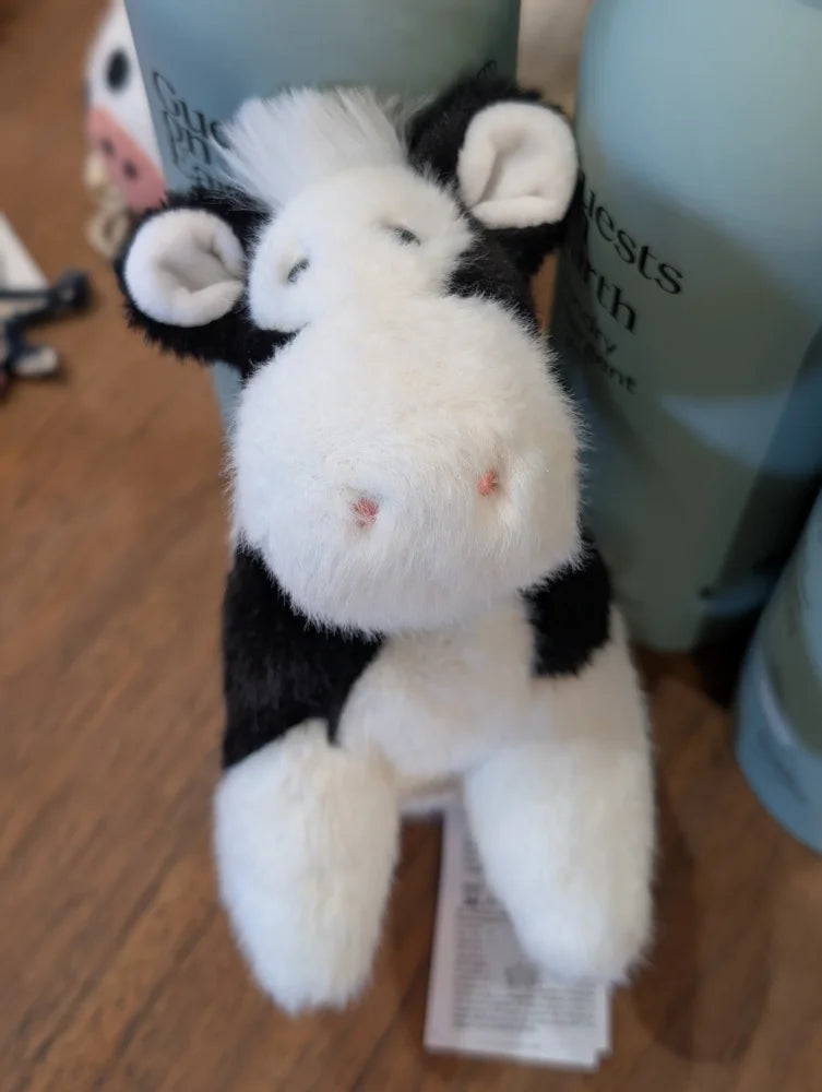 A plush black white cow toy with soft fluffy fur and a giant snuggly muzzle perfect for cuddling