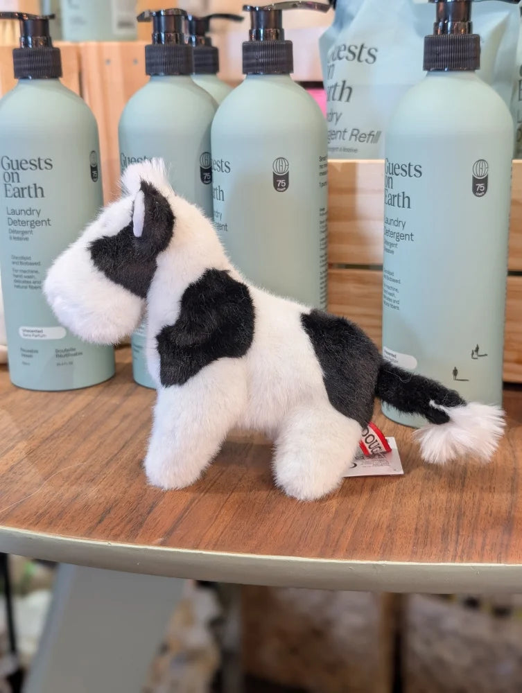 A plush black white cow toy with giant snuggly muzzle and soft fur standing on a wooden surface