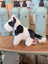 A plush black white cow toy with giant snuggly muzzle and soft fur standing on a wooden surface