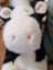 A plush black white cow toy with fluffy fur and a giant snuggly muzzle featuring soft pink nose details