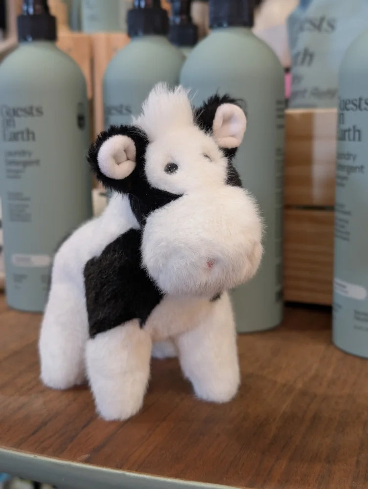 A black white cow plush toy with soft fluffy fur and a giant snuggly muzzle perfect for cuddling