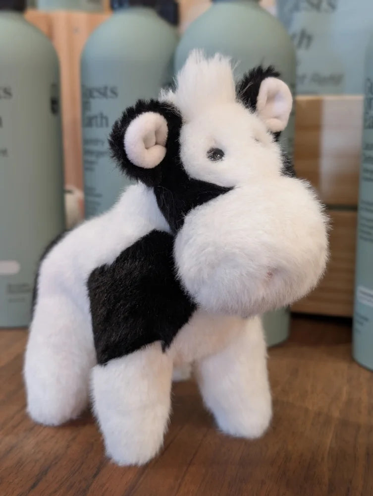 A plush black white cow toy with soft fluffy fur and a giant snuggly muzzle perfect for cuddling