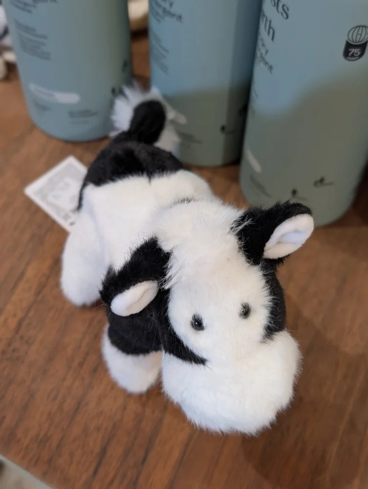 A plush black white cow toy with soft, fluffy fur and a giant snuggly muzzle for cozy hugs