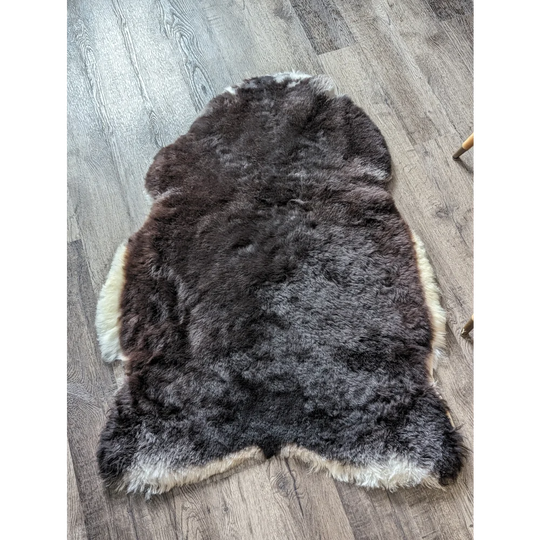 A plush icelandic sheepskin rug with dark brown to black gradient and white sides in medium spotted icelandic style
