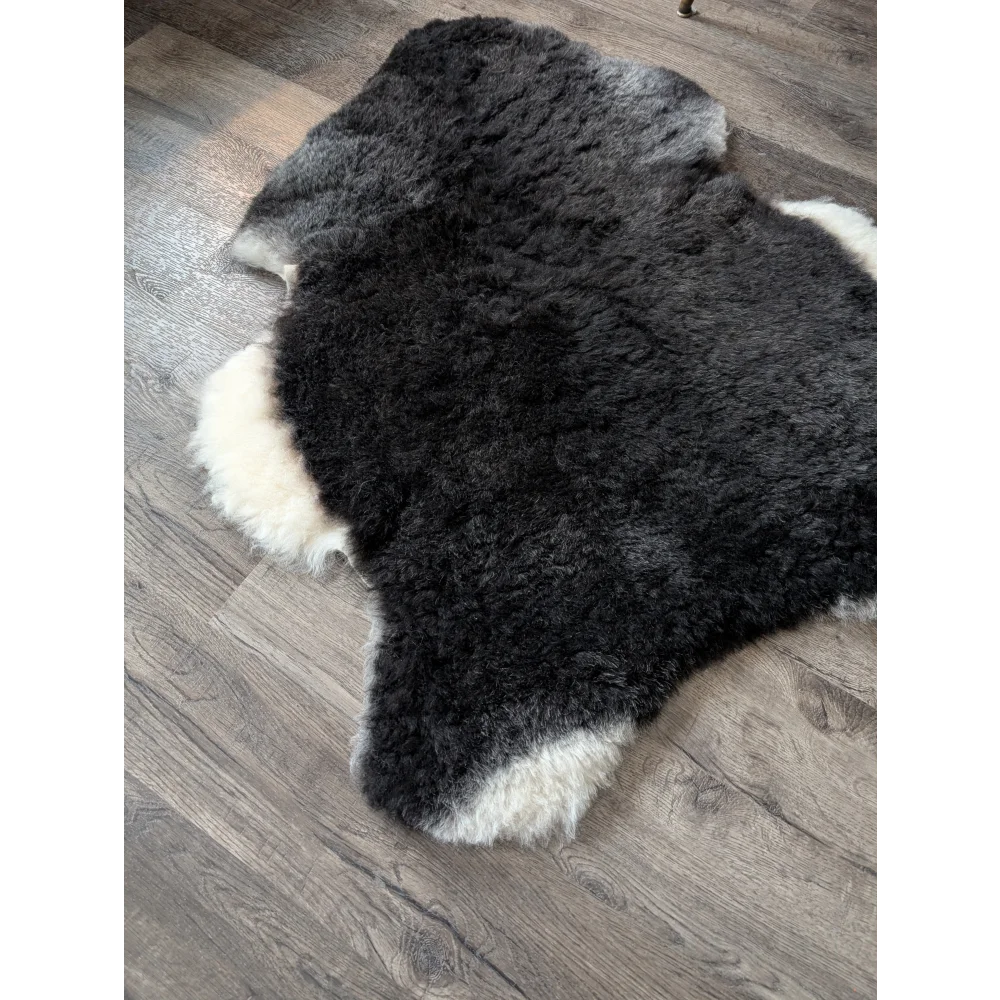 A plush black with white sides icelandic sheepskin rug with a soft medium spotted natural wool pattern