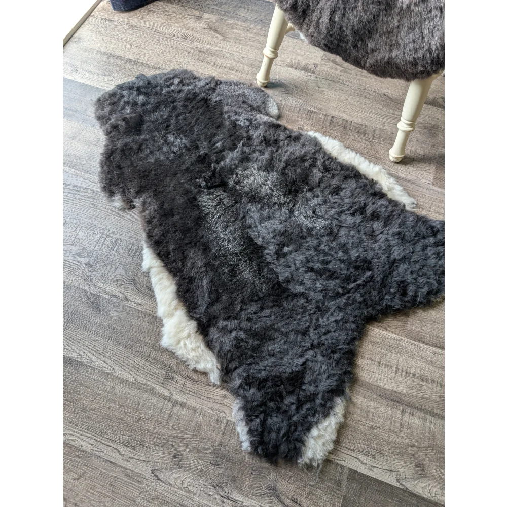 A black with white sides icelandic sheepskin rug with soft curly medium spotted icelandic wool texture on the floor