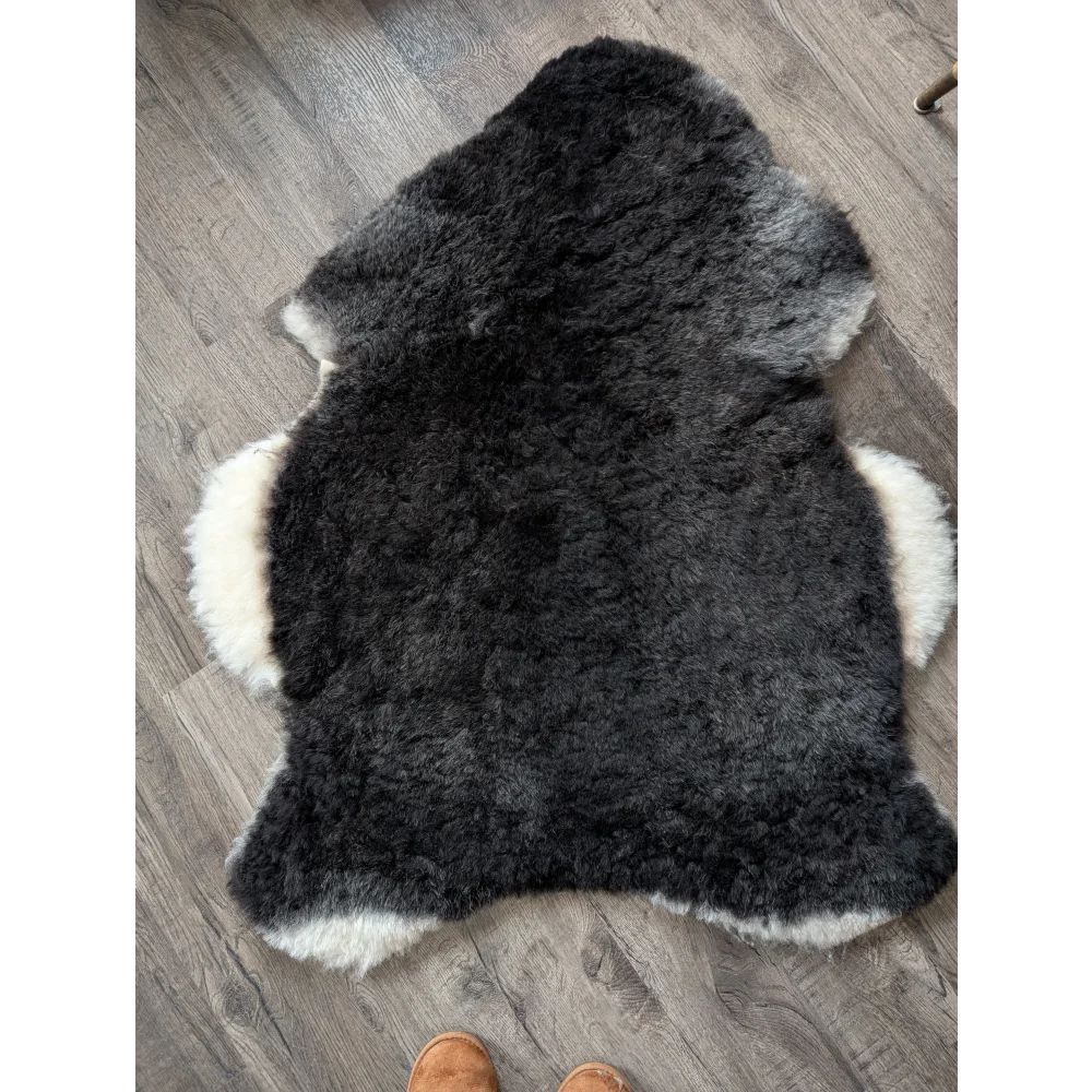 A plush icelandic sheepskin rug with a black center and white edges made of soft short wool perfect for cozy spaces