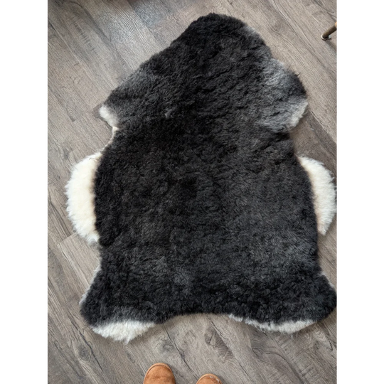 A plush icelandic sheepskin rug with a black center and white edges made of soft short wool perfect for cozy spaces