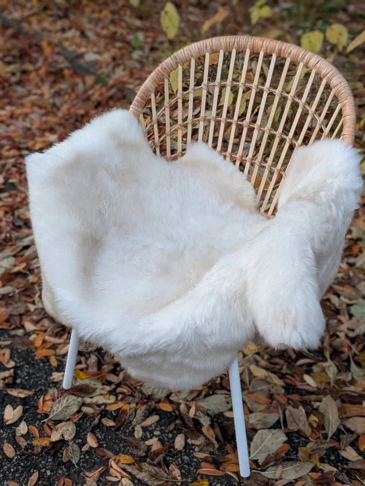 White faux fur throw made from very soft british isles sheepskin draped over a wicker chair