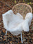 White faux fur throw made from very soft british isles sheepskin draped over a wicker chair