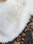 A plush white faux fur blanket with a soft fluffy texture made from british isles sheepskin, 46 by 31 inches
