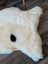 A fluffy white british isles sheepskin rug with a single black spot in the center measuring 48 by 32 inches