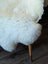 A plush off-white british isles sheepskin chair with soft fluffy texture and wooden legs perfect for cozy seating